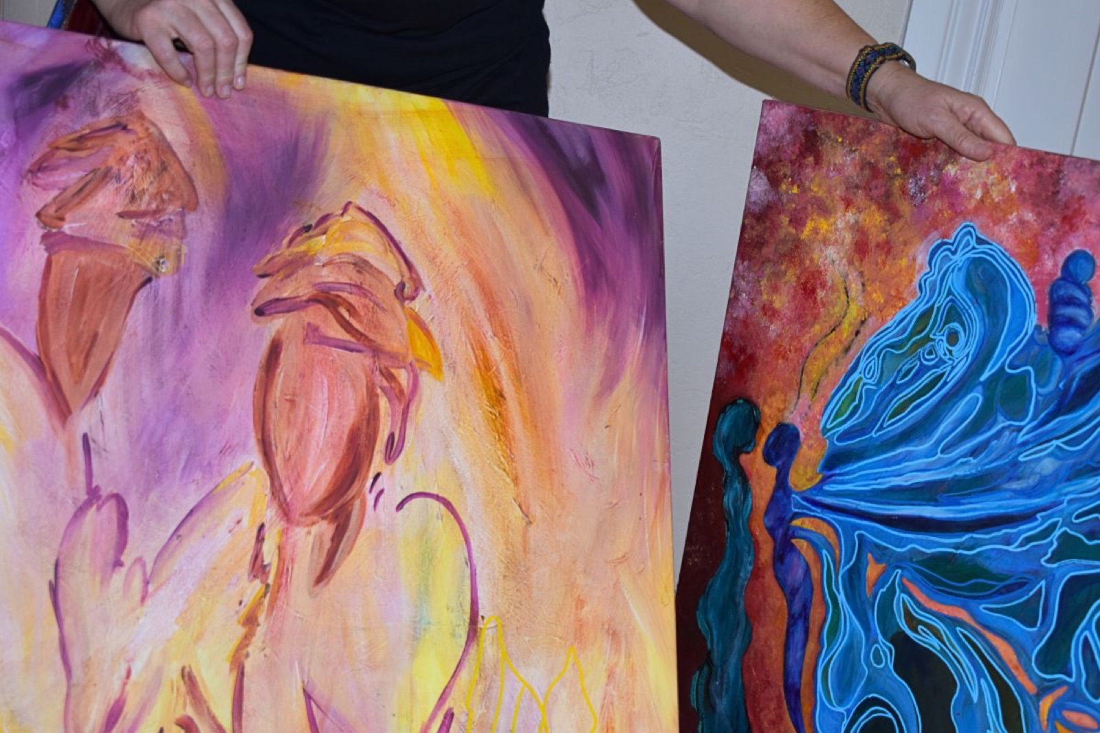 Diane holding two large canvases in progress in her studio